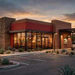 Taco Bueno restaurant storefront with drive-thru at dusk