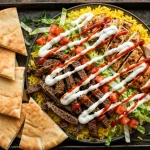 The Halal Guys secret menu loaded platter with white sauce drizzle