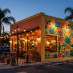 Tijuana Flats Tex-Mex restaurant storefront at dusk with glowing windows and mural art